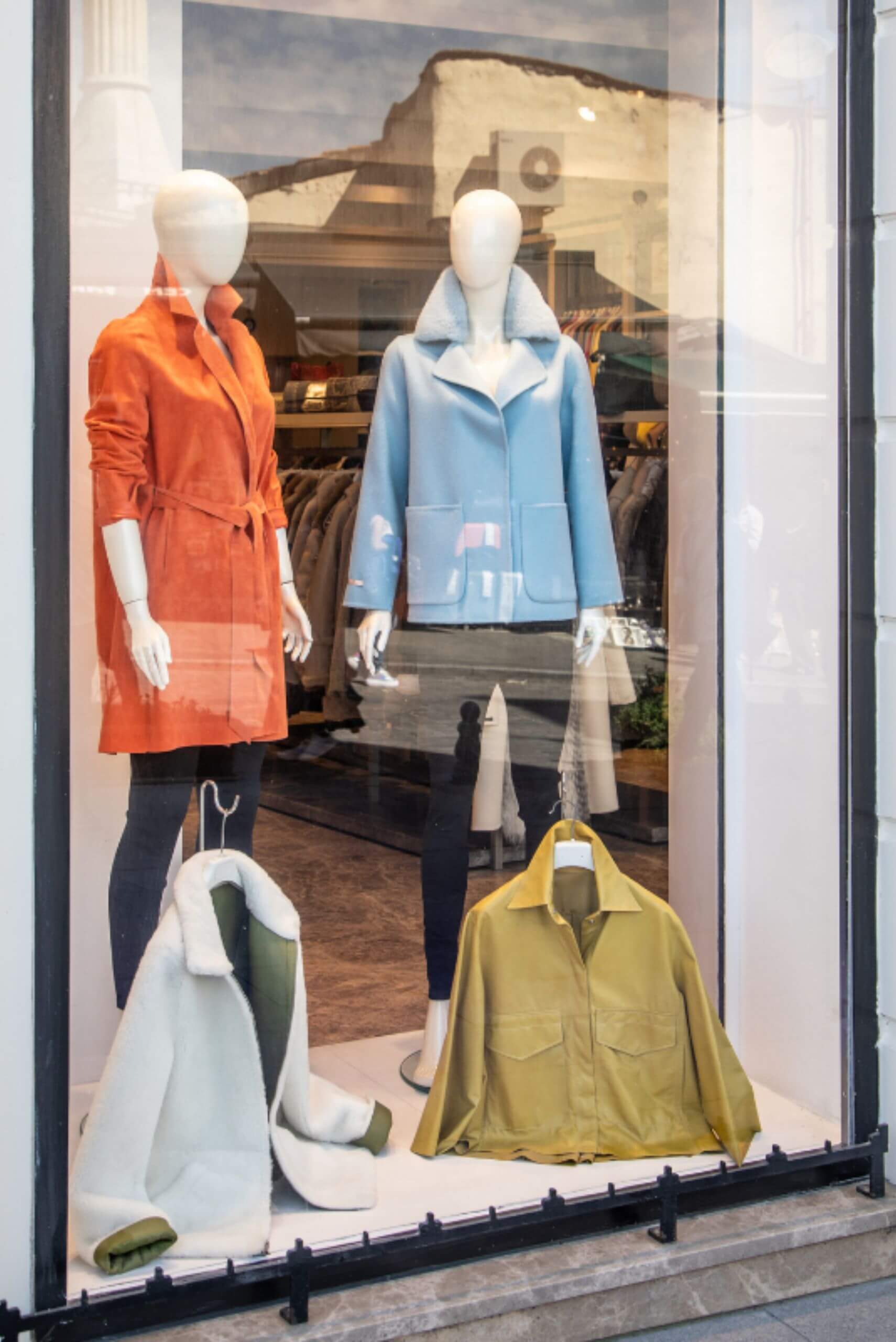 a storefront window with mannequins wearing different colored leather jackets