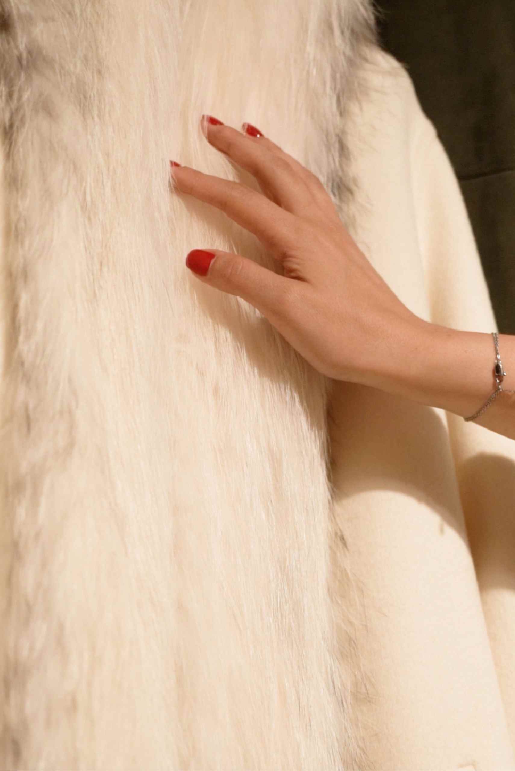 Close-up of a luxury white fur coat as a hand touches the soft texture, highlighting genuine fur quality and craftsmanship in Istanbul