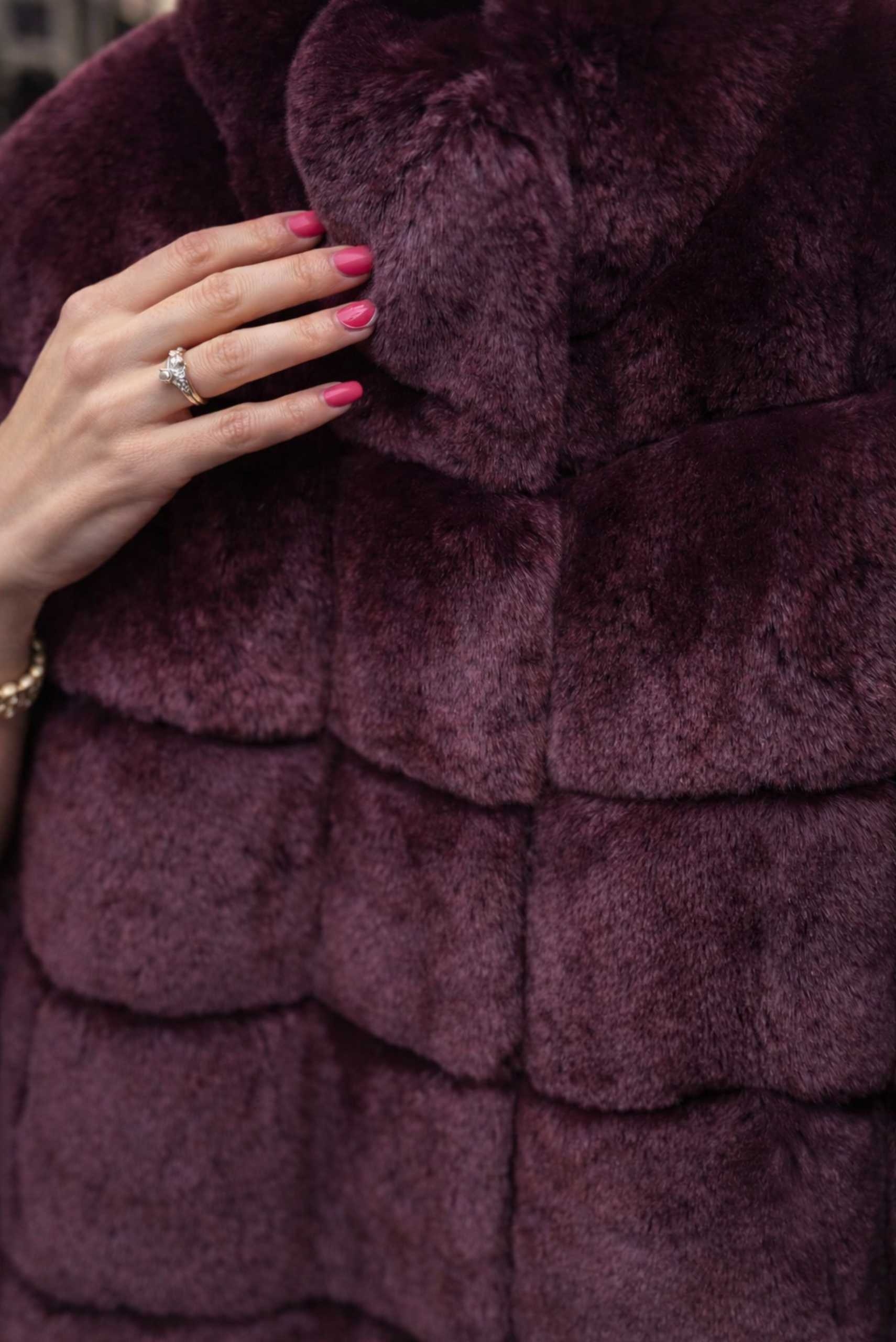 Close-up of a luxury chinchilla fur coat highlighting fine details and soft texture with a woman’s hand